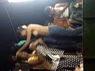 A dancer without a top hesitates around her companions and the general public in a vehicle